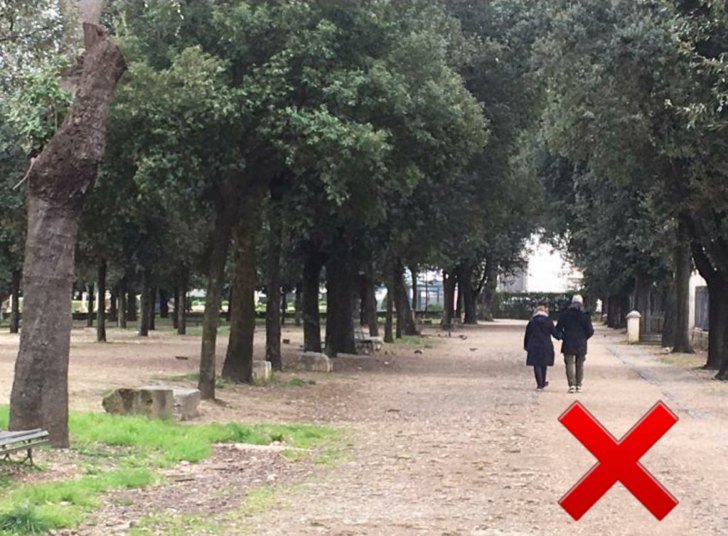 Una coppia passeggia per Villa Borghese mano nella mano. Sbagliato.