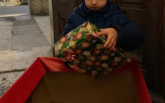 Un bimbo dona un pacco regalo per la raccolta 