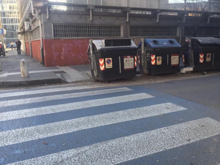 Cassonetti in prossimità di un attraversamento pedonale. Foto dalla pagina Facebook di Renato Sartini 